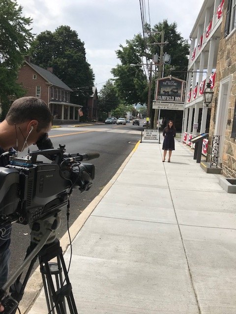 behind the scenes photo: guest standing in front of restaurant while camera operator records footage